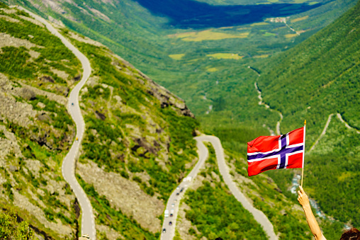 Norwegian flag and Trolls Path Trollstigen winding scenic mountain road in Norway Europe. National tourist route.