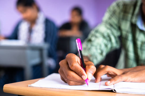 scatto ravvicinato di studenti universitari che scrivono appunti sul libro in classe - concetto di esame, sviluppo e istruzione - medical exam foto e immagini stock