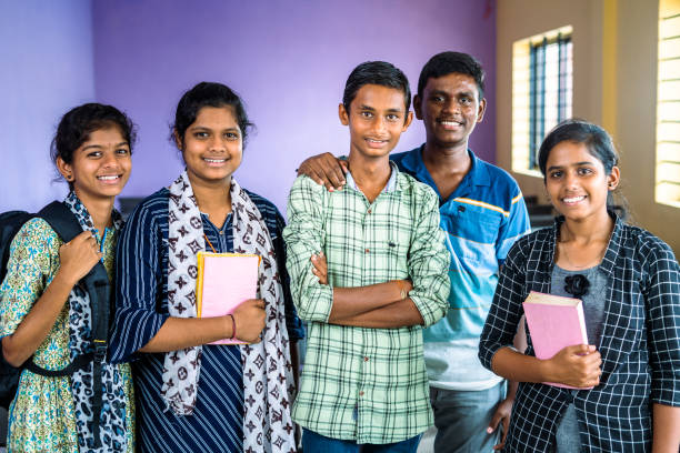 group of college students confidently standing with books and backpack at classroom by looking at camera - concept of education, friendship and classmates.