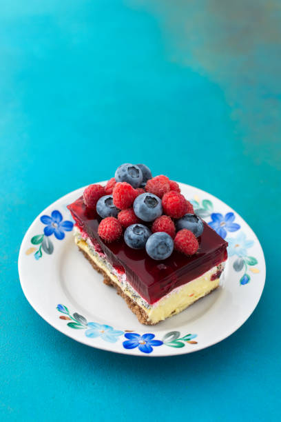 A piece of cake with poppy seeds and berry jelly, cake on a plate decorated with juicy raspberries and blueberries