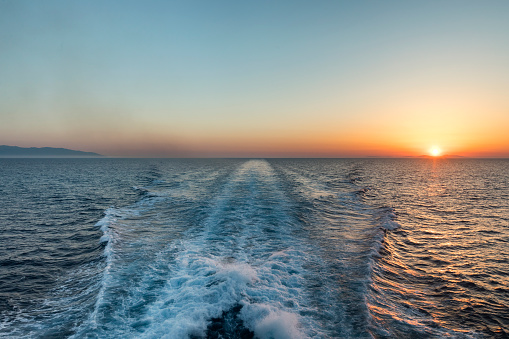 Sunset view of the sea taken from a ferry boat in the Cyclades islands of Greece in Europe and representing the desire of travel.