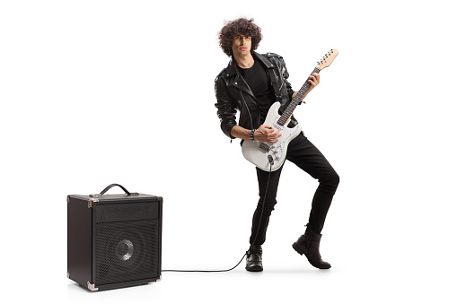 Male young adult jumping and playing an electric guitar isolated on white background