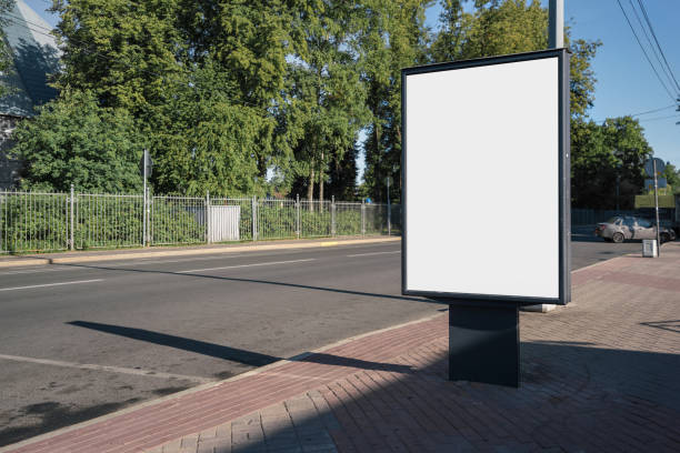 istock Empty vertical white poster with mockup space stands on city sidewalk. 1409839188