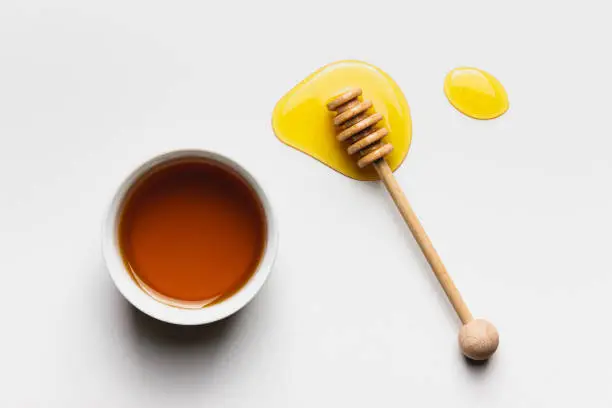 Honey in bowl on white background. Top view of healthy ingredient.