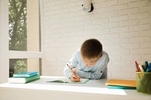 istock A schoolboy writes numbers in a notebook at a white desk. Back to school 1409840850