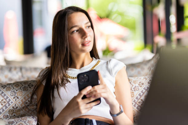 istock Smiling young woman in cafe using mobile phone and texting in social networks, sitting alone 1409841654