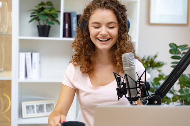 istock Young curly female recording podcast from home and talking into a microphone 1409844730