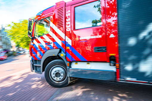 Fire engine rushing to the scene of an accident in the city of Delft in South-Holland, The Netherlands during a summer day.