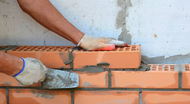 istock Close up on bricklaer hands laying house brick wall with  trowel. 1409844815