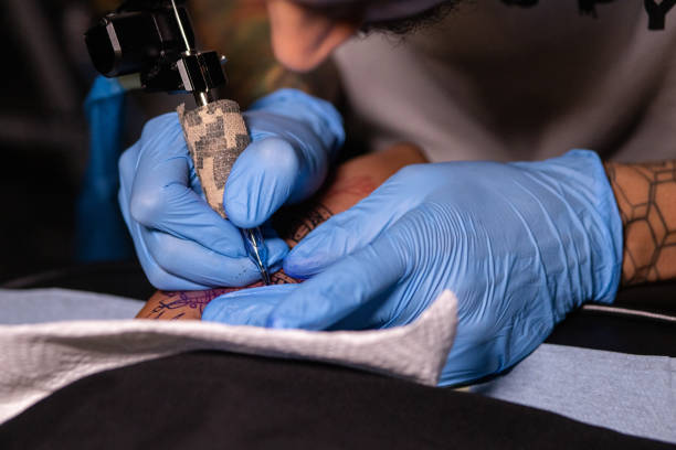 istock Young tattoo artist focused on tattooing his client 1409845209
