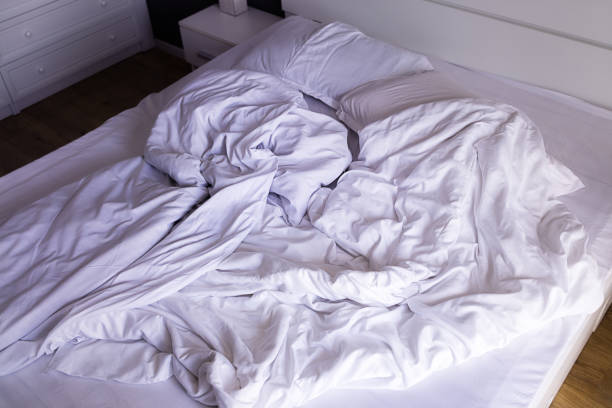 istock Unmade double bed with white linens in the morning 1409845526