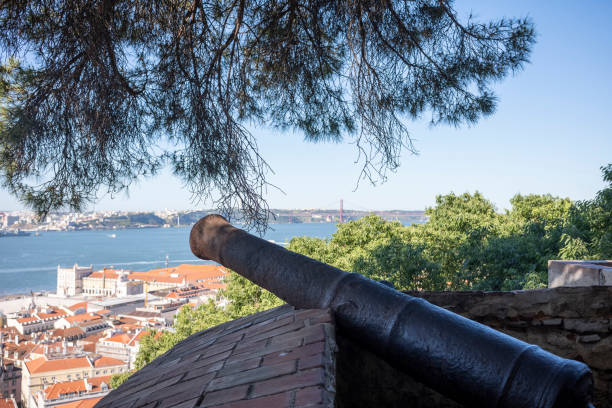 Lisbon, Portugal - May 26, 2022: View over the old town of Lisbon to the red bridge of April 25th from the Castle of São Jorge in the day in summer without people with trees.