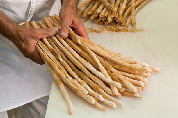 Breadsticks Male baker hold fresh baked grissini, an italian torinese food specialty piedmont italy photos stock pictures, royalty-free photos & images