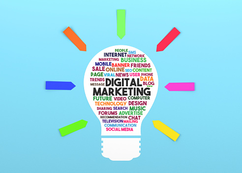 Paper in the shape of a lightbulb and the words Digital Marketing on it. Blue background and colorful sticky note papers.