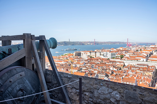 Lisbon, Portugal - May 26, 2022: View over the old town of Lisbon to the red bridge of April 25th from the Castle of São Jorge in the day in summer without people with trees.