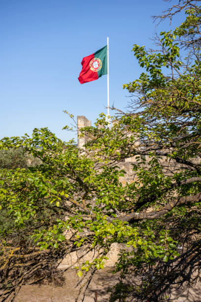 Lisbon, Portugal - May 26, 2022: Portuguese flag at the Castle of São Jorge in the day with sunshine without people.
