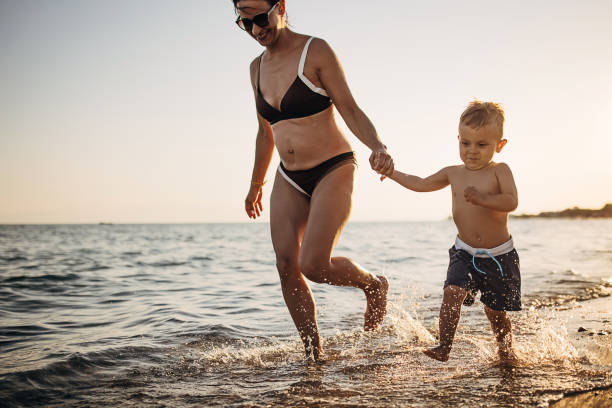 istock Mother and son holding hands and walking on the beach 1409850439
