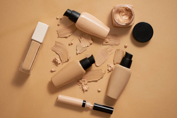 Bottles of makeup foundation and samples on beige background