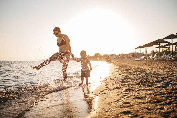 istock Mother and son holding hands and walking on the beach 1409850846