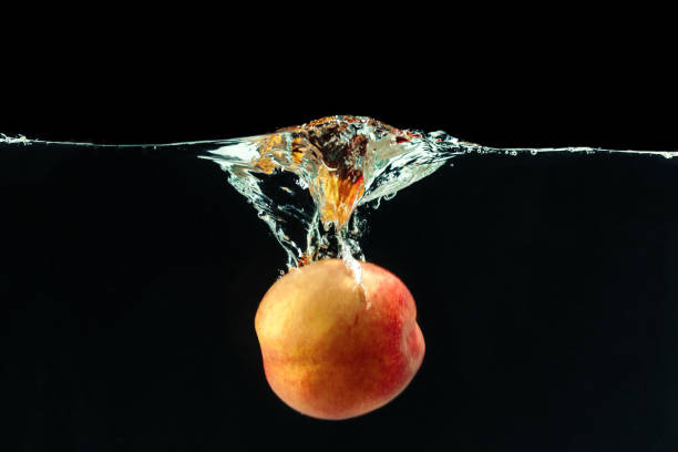 Peach dropped into water with bubbles