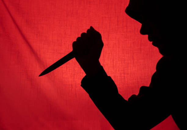 Danger! Young woman brandishing a sharp meat cleaver as she parts the drapes at a doorway.