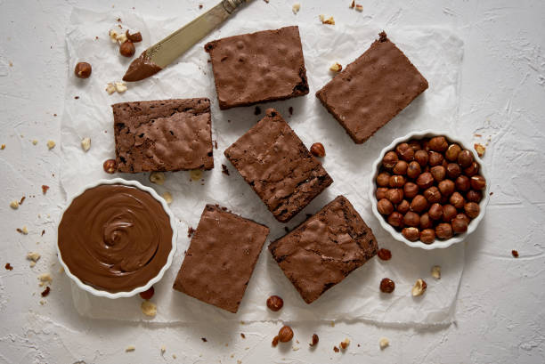 świeże domowe czekoladowe brownie podane z orzechami laskowymi i roztopioną śmietaną - nut pastry brownie hazelnut zdjęcia i obrazy z banku zdjęć