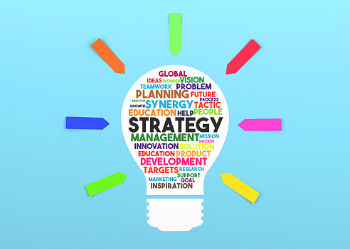 Paper in the shape of a lightbulb and the words Strategy on it. Blue background and colorful sticky note papers.