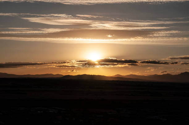 istock sunset behind the mountain. Sun behind Clouds in Madrid nature landscape 1409852675