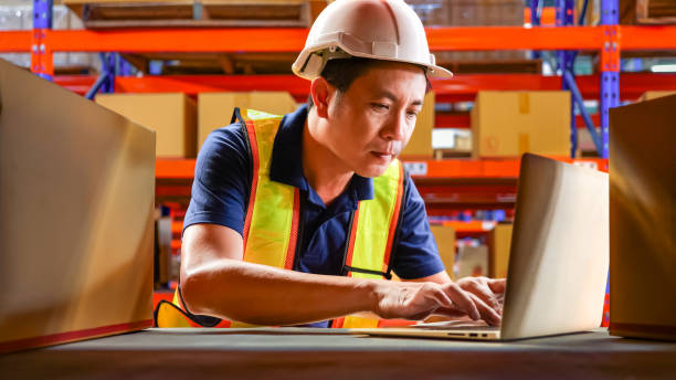istock Portrait of hardworking warehouse manager using computer laptop in warehouse with cardboard boxes on shelves background, Warehouse worker portrait 1409854178