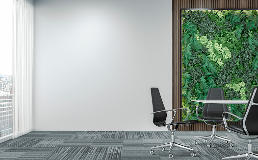 Empty unfurnished office interior with a conference table and chairs in front of the vertical garden (green plants wall) lush foliage of potted plants (fern, moss, succulents) and partly dark brown paneled hardwood wall, partly white plaster wall background with copy space on gray carpet floor and windows in the background. 3D rendered image.