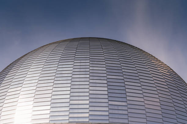 Silver glazed tiles on a dome of a building with a sun reflection against dark blue sky
