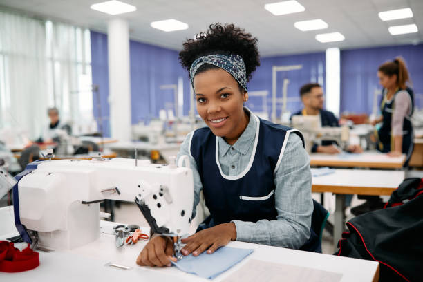 istock Happy black dressmaker sewing while working on production line in a factory. 1409860220