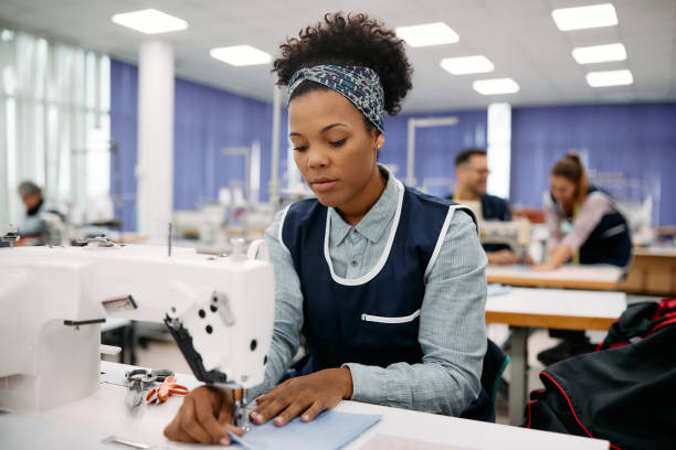 istock Young black seamstress working at textile factory. 1409860333