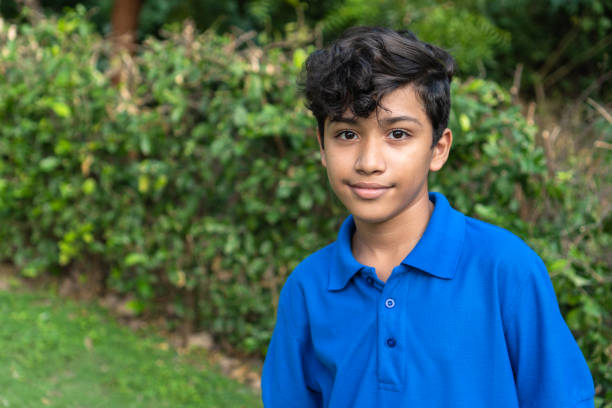 A young man looks directly into the camera in a rural setting.