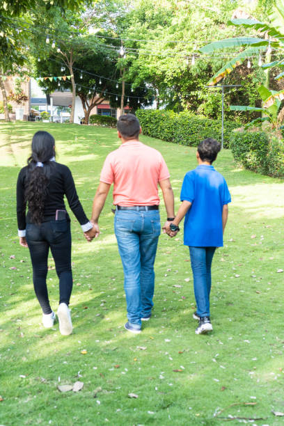 istock Father walking through a field with his children holding his hands 1409861218