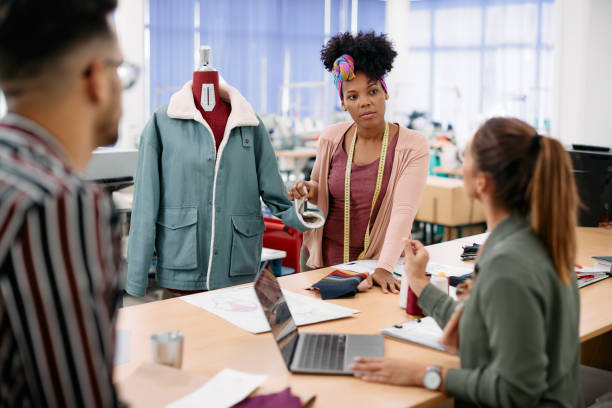 istock Black clothing designer talking to her colleagues while working in a studio. 1409861755