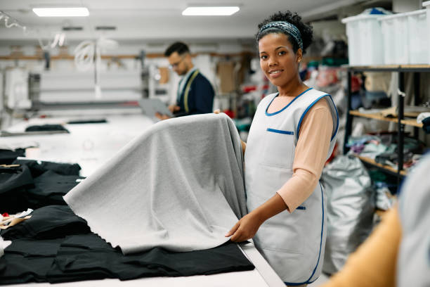 istock Happy African American seamstress working with fabric at textile workshop and looking at camera. 1409862617
