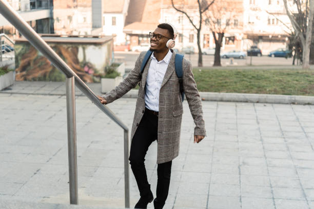 istock Young African man enjoying music while walking after work 1409862826