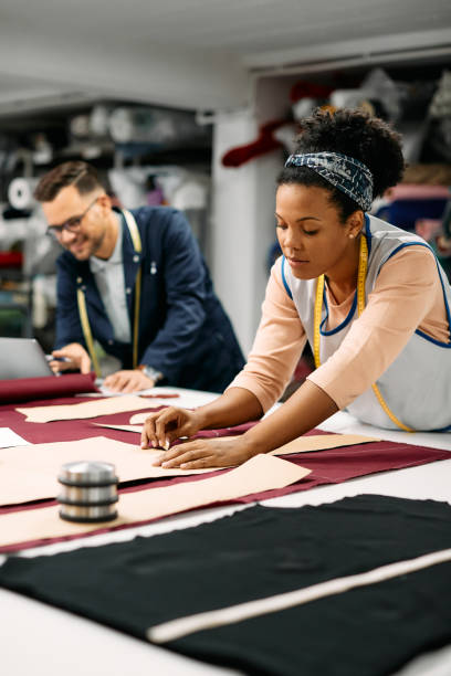 istock African American textile worker marking fabric with chalk at tailor's workshop. 1409862879