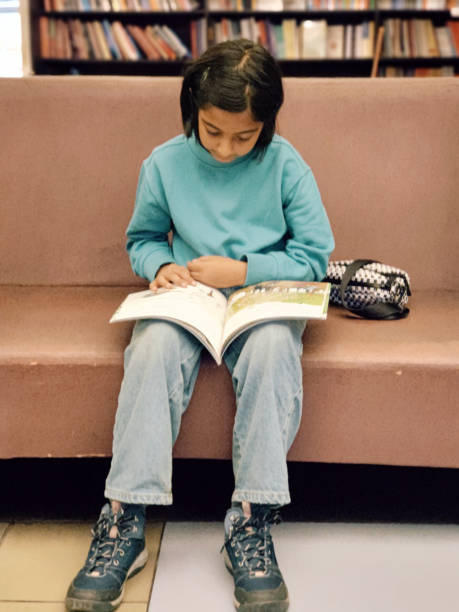 istock Girl sitting in a library and reading a book 1409863407