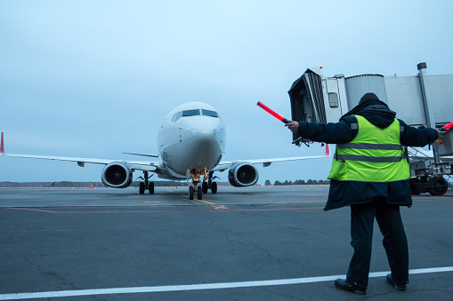 Aircraft marshalling at the aiport apron. Passenger airplane meeting