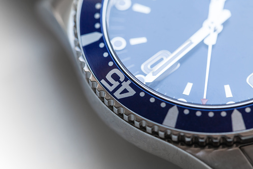 Automatic mechanical Swiss made wrist watch fragment with blue deal and rotating ceramic bezel. Closeup photo with selective soft focus