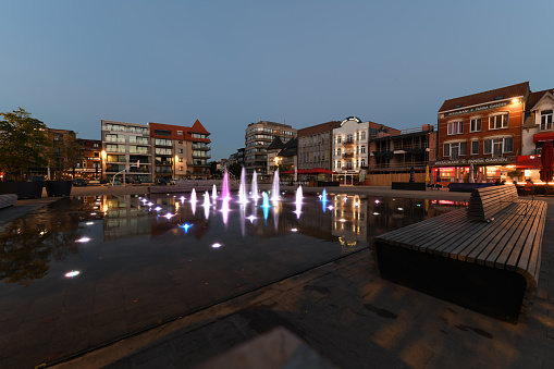 De Panne, Belgium. 15 July 2022. Water fountain in town square of De Panne, Belgium at dusk.