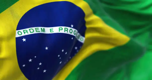 Close-up view of the Brazilian national flag waving in the wind. Brazil is a South American country. Fabric background