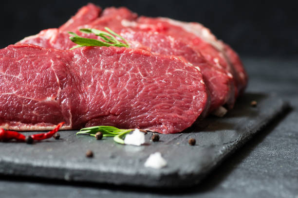 raw beef steak meat on stone board with thyme and peppers, butcher concept - sirloin steak fotos imagens e fotografias de stock