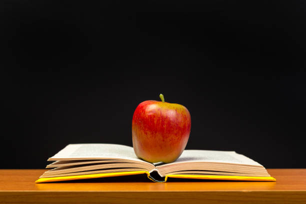 red apple and old books on wooden tabletop
