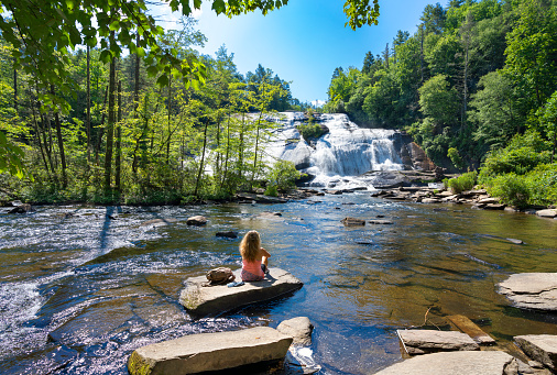 Woman relaxing by the lake. High Falls  of Dupont State Forest in Brevard. Blue Ridge Mountains, near Asheville, Western North Carolina, USA.
