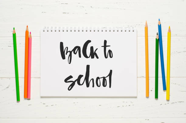 istock Children's accessories for study, creativity and office supplies on a white wooden background. Handwritten inscription Back to school on a white notebook. 1409869667