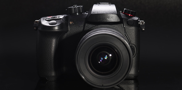 Closeup of professional camera with black background. Sale of photographic equipment concept