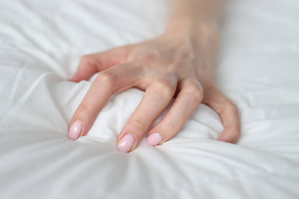istock Woman hand tightly grips white sheet on bed 1409873471